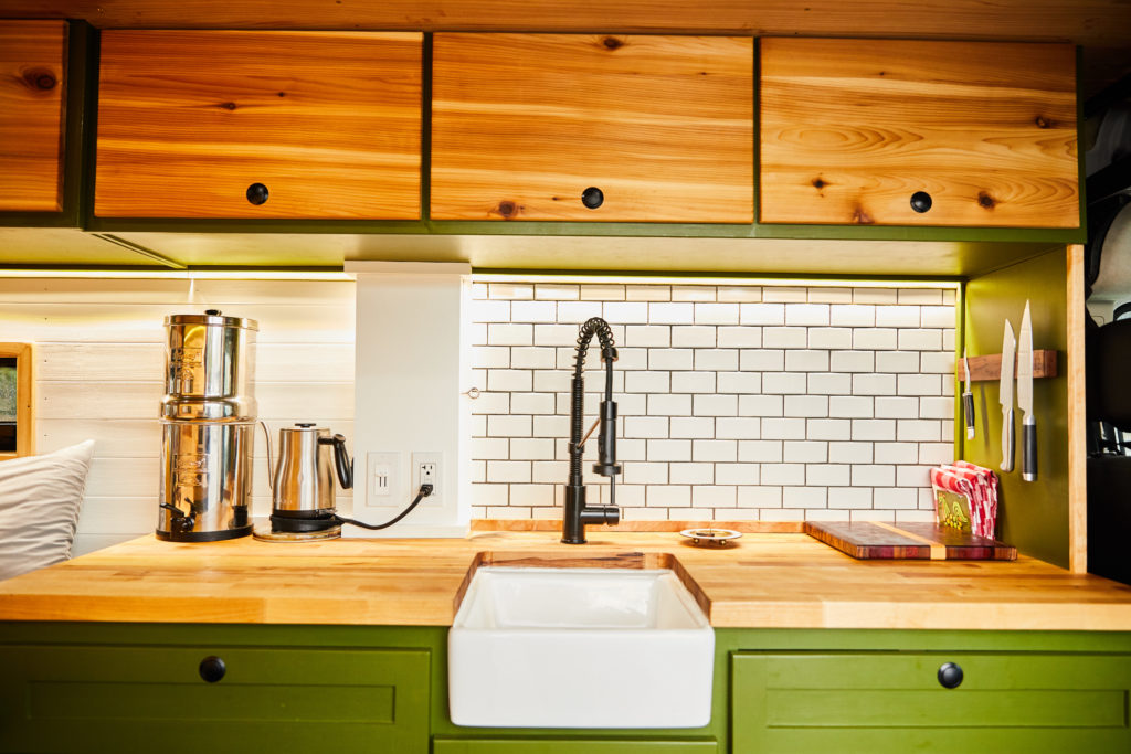 Camper van kitchen with subway tile backsplash and farmhouse sink