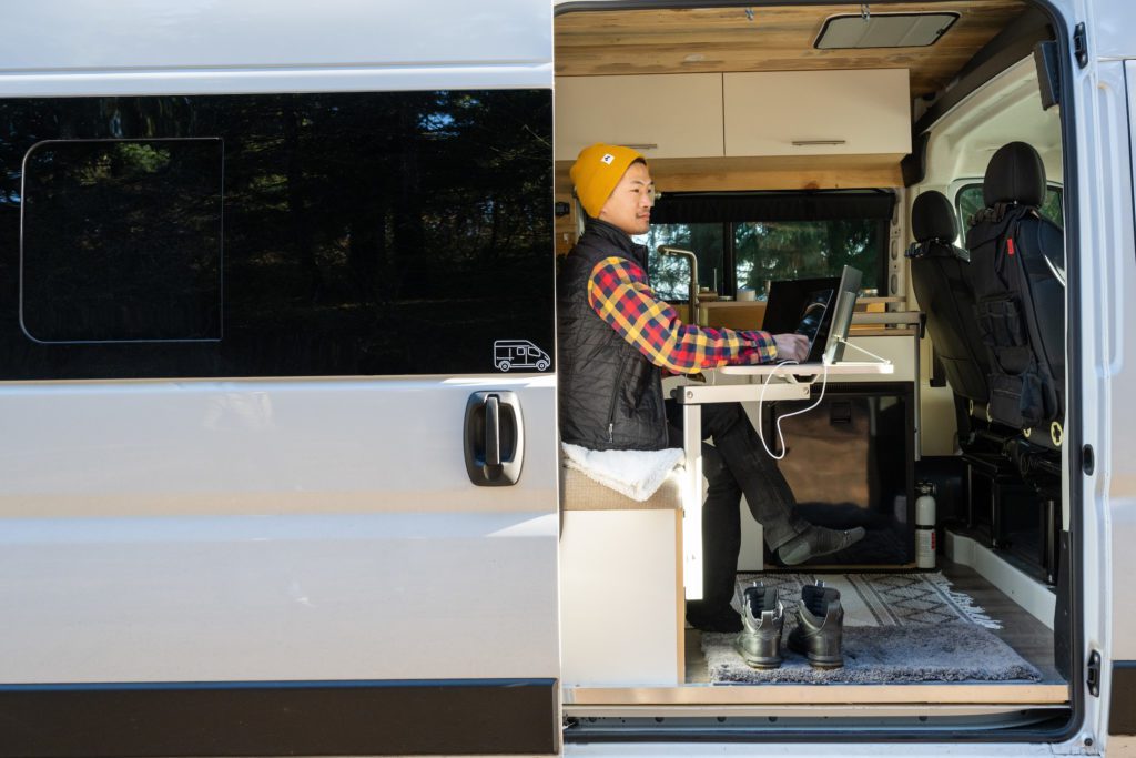 Person sits in a van and works off of Epic Off-Grid WiFi router.