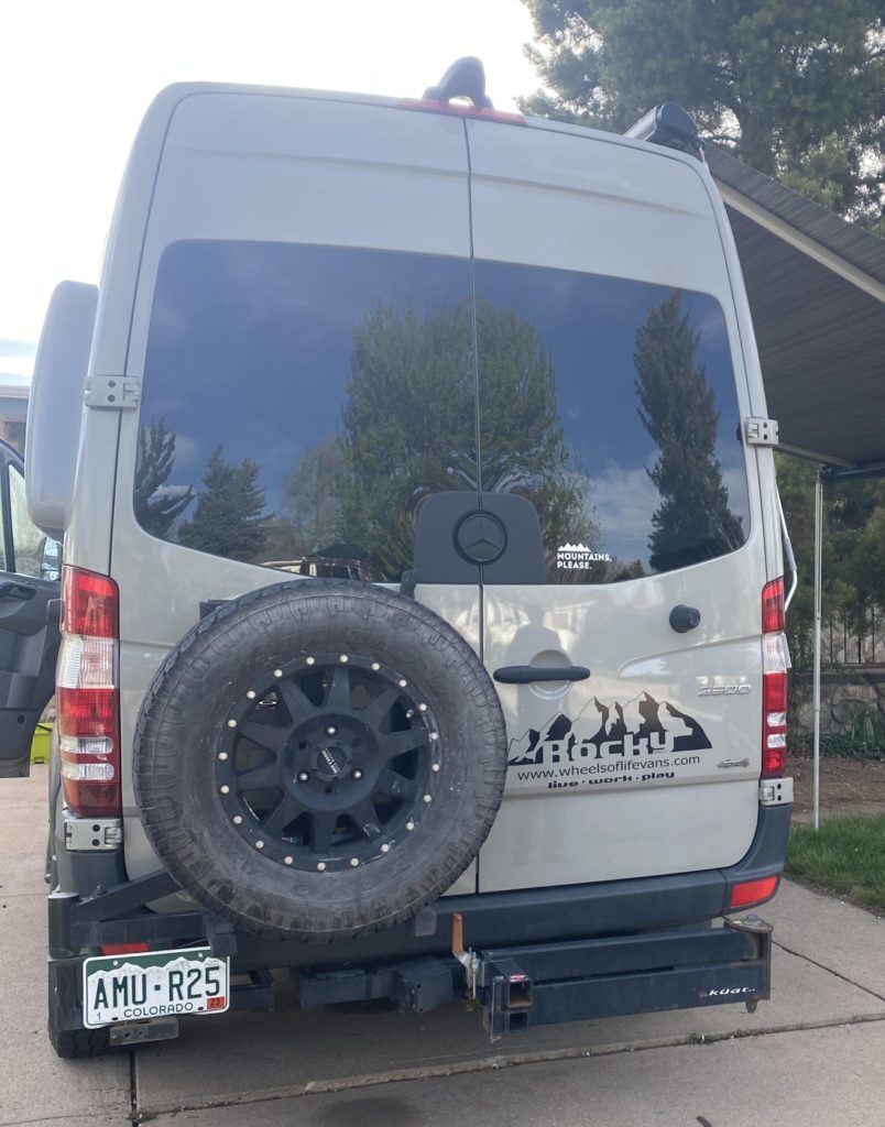 A 4x4 Mercedes-Benz Sprinter camper van is parked with the rear doors closed.