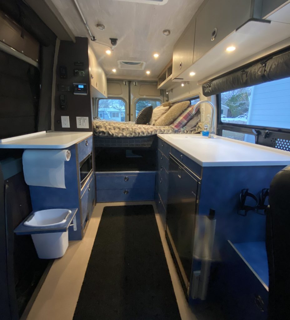 The view from the front shows a galley kitchen and platform bed.